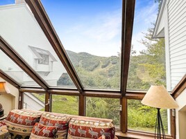 Una habitación con un tragaluz grande, un sofá con cojines estampados y una lámpara.