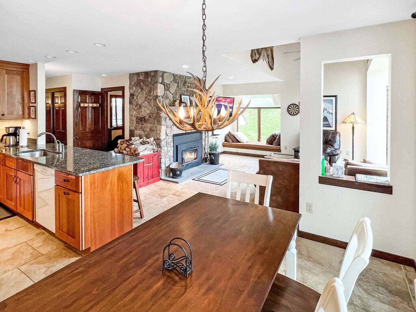 A spacious kitchen with a stone accent wall, a dining area with a wooden table, and a fireplace.