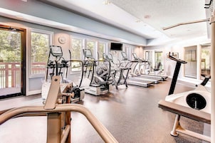 Un gimnasio con cintas de correr, elípticas y una máquina de remo.