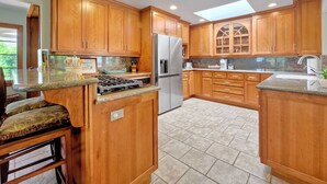 A kitchen with wooden cabinets, a stainless steel refrigerator, and a gas stove. - 5051 Shore Drive (Carlsbad)