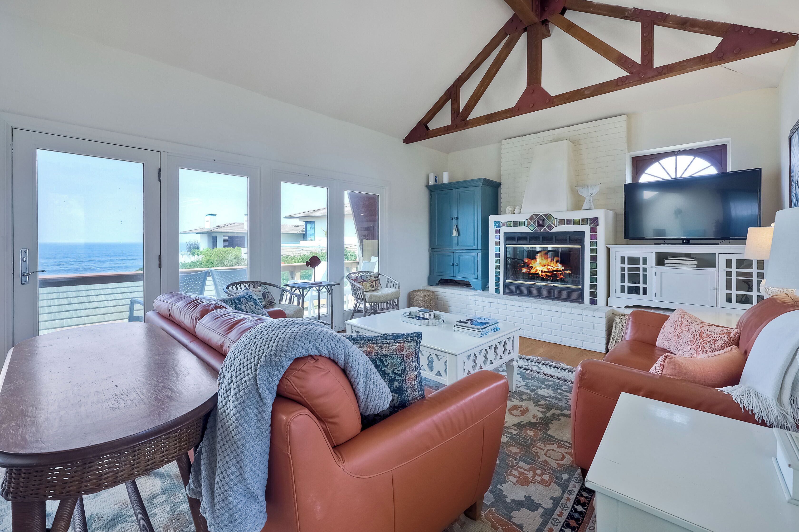 Ein Wohnzimmer mit Kamin, Fernseher und Meerblick.