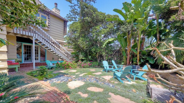 A backyard with a patio area, outdoor seating, and a staircase leading to a covered porch. - 5051 Shore Drive (Carlsbad)