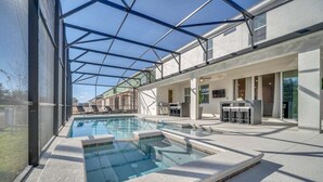 A modern indoor pool area with clear glass ceilings, a pool, and lounge seating. - 2525 Shanti Amazing 15 Suites Mansion (Kissimmee)