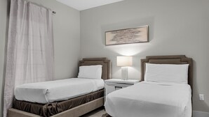 A hotel room with two beds, a nightstand with a lamp, a painting on the wall, and a curtain. - 7108 (Orlando)