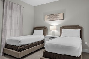 Ein Hotelzimmer mit zwei Betten, einem Nachttisch mit Lampe, einem Bild an der Wand und einem Vorhang.