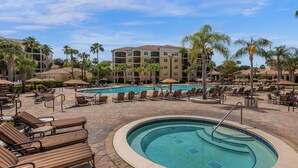 A resort pool area with lounge chairs, a central pool, and palm trees. - 7108 (Orlando)