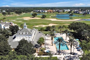 A golf course with a swimming pool and lounge area, surrounded by residential buildings. - 7909 Draw Street 3bed (Kissimmee)