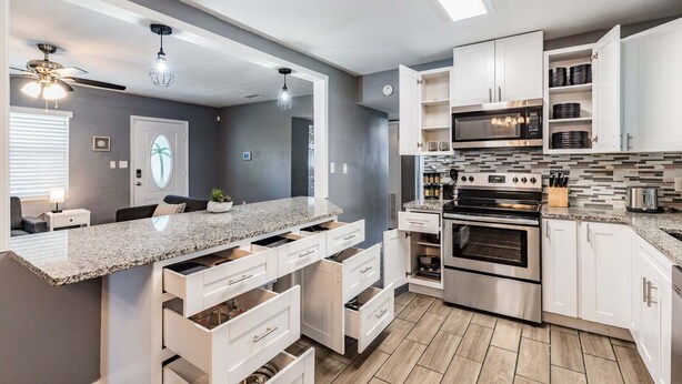 Una cocina moderna con encimera de granito, electrodomésticos de acero inoxidable y armarios blancos.