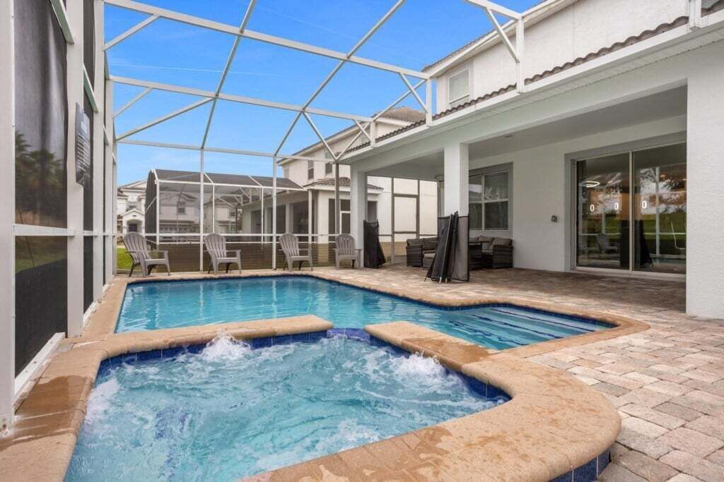 A swimming pool with a hot tub, outdoor seating, and a covered patio area.