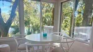 Een ronde tafel met stoelen, een blauwgroene kop en een witte hek buiten.