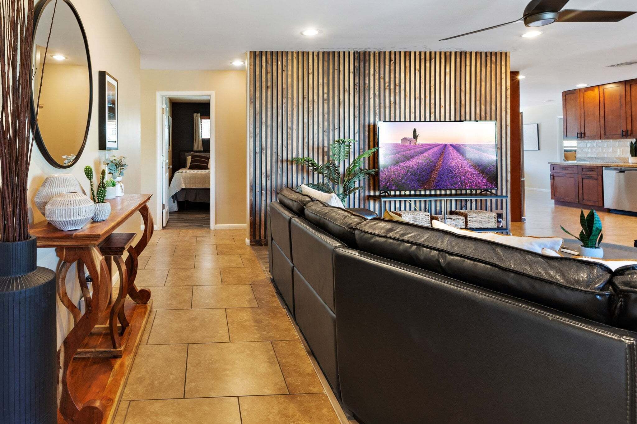 A modern living room with a leather sofa, a TV, and a wooden wall panel.