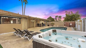 Zona de piscina con sillones de descanso, jacuzzi y terraza cubierta.
