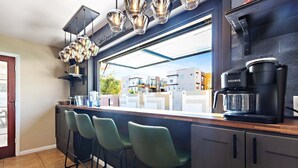 Una cocina moderna con barra, cafetera y vistas al barrio.