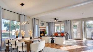 Ein großzügiger Wohnbereich mit Esstisch, Stühlen, Sofas und einem Kamin.