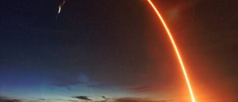 A rocket launch with a bright orange arc against a starry night sky.