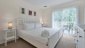 A bedroom with a bed, bedside tables, a dresser, and a window with blinds. - 8460 Crystal Cove Loop 3bed (Kissimmee)
