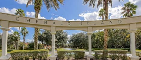 A sign reading 'Emerald Island' with a clear sky and palm trees in the background.