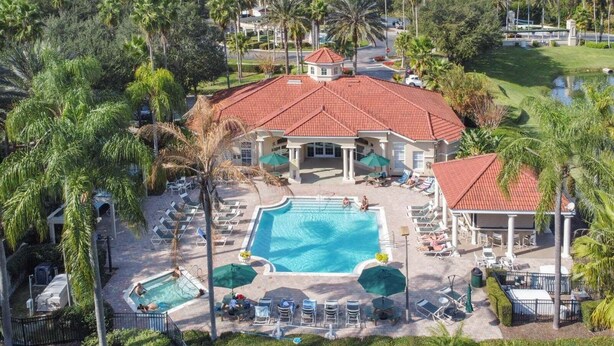 A resort with a large swimming pool, lounge chairs, and palm trees. - 8460 Crystal Cove Loop 3bed (Kissimmee)