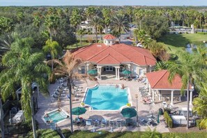 A resort with a large swimming pool, lounge chairs, and palm trees. - 8460 Crystal Cove Loop 3bed (Kissimmee)
