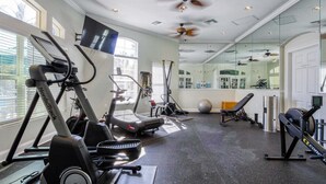 A gym with treadmills, elliptical machines, a rowing machine, and a bench press area. - 8460 Crystal Cove Loop 3bed (Kissimmee)