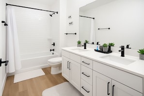 A modern bathroom with a bathtub, toilet, and a vanity with a mirror. - Iconic Design Home In Workerfriendly A+location (Sherman)