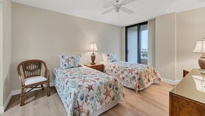 A bedroom with two beds, a ceiling fan, a chair, and a nightstand with a lamp. - Anc903 (Siesta Key)