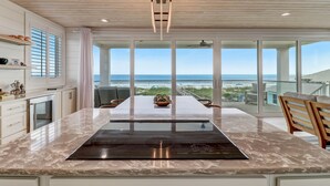 Una cucina moderna con una grande isola, una zona pranzo e vista sulla spiaggia.