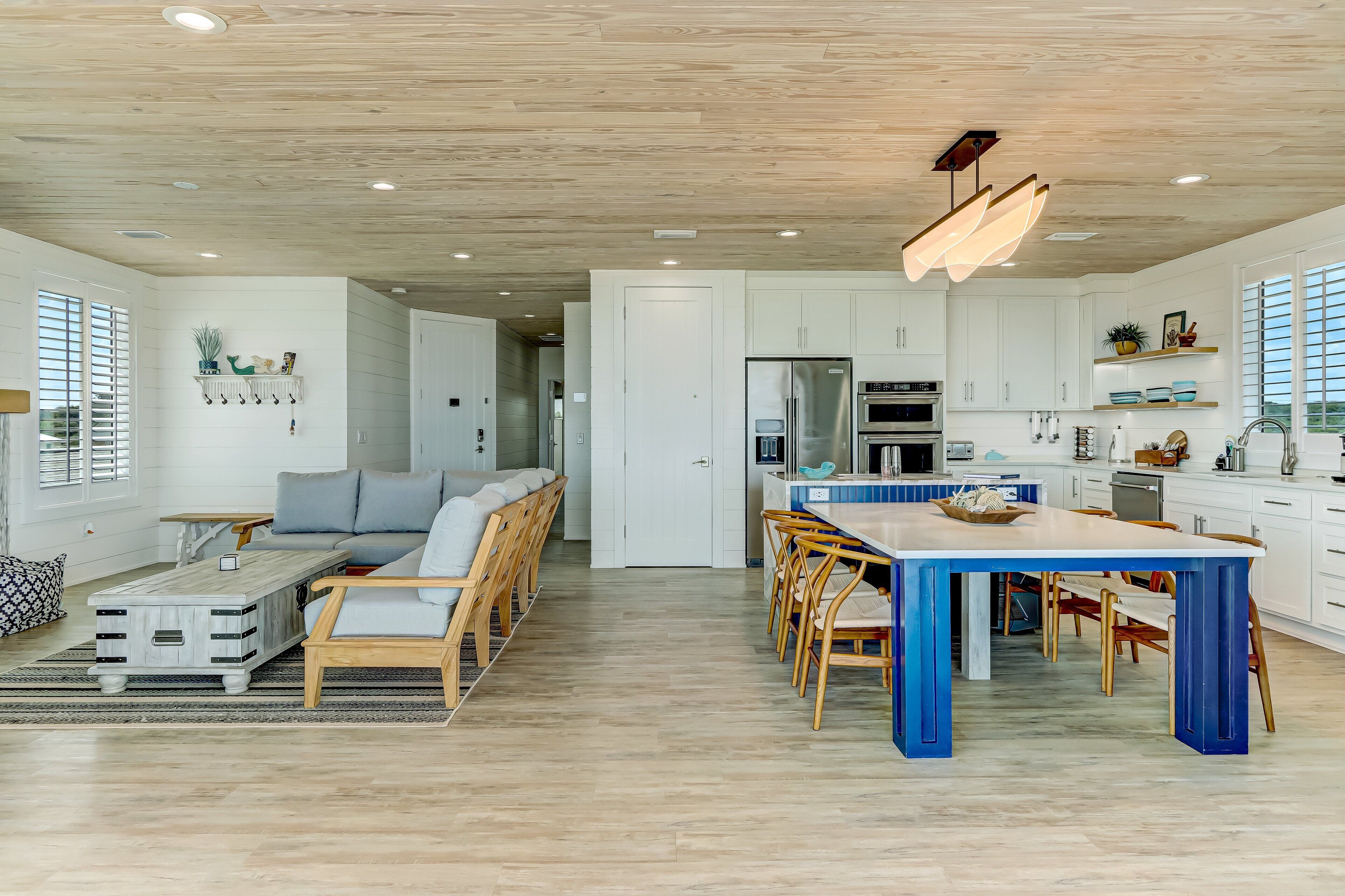 Een ruime woonkamer met een bank, eettafel en een keuken op de achtergrond.