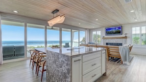 Una cucina moderna con una grande isola, soffitto in legno e ampie finestre con vista sull'oceano.