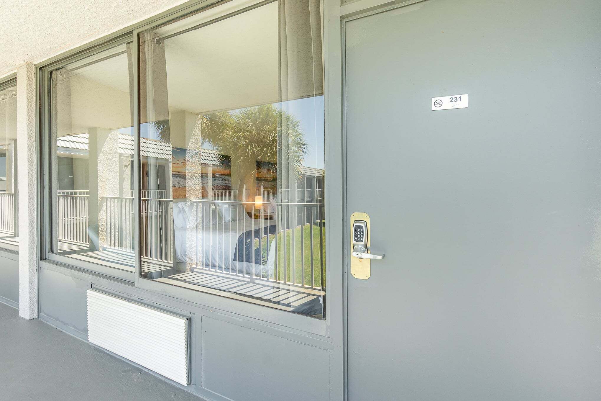 A door with a keypad lock, a window with a metal railing, and a number sign above the door.