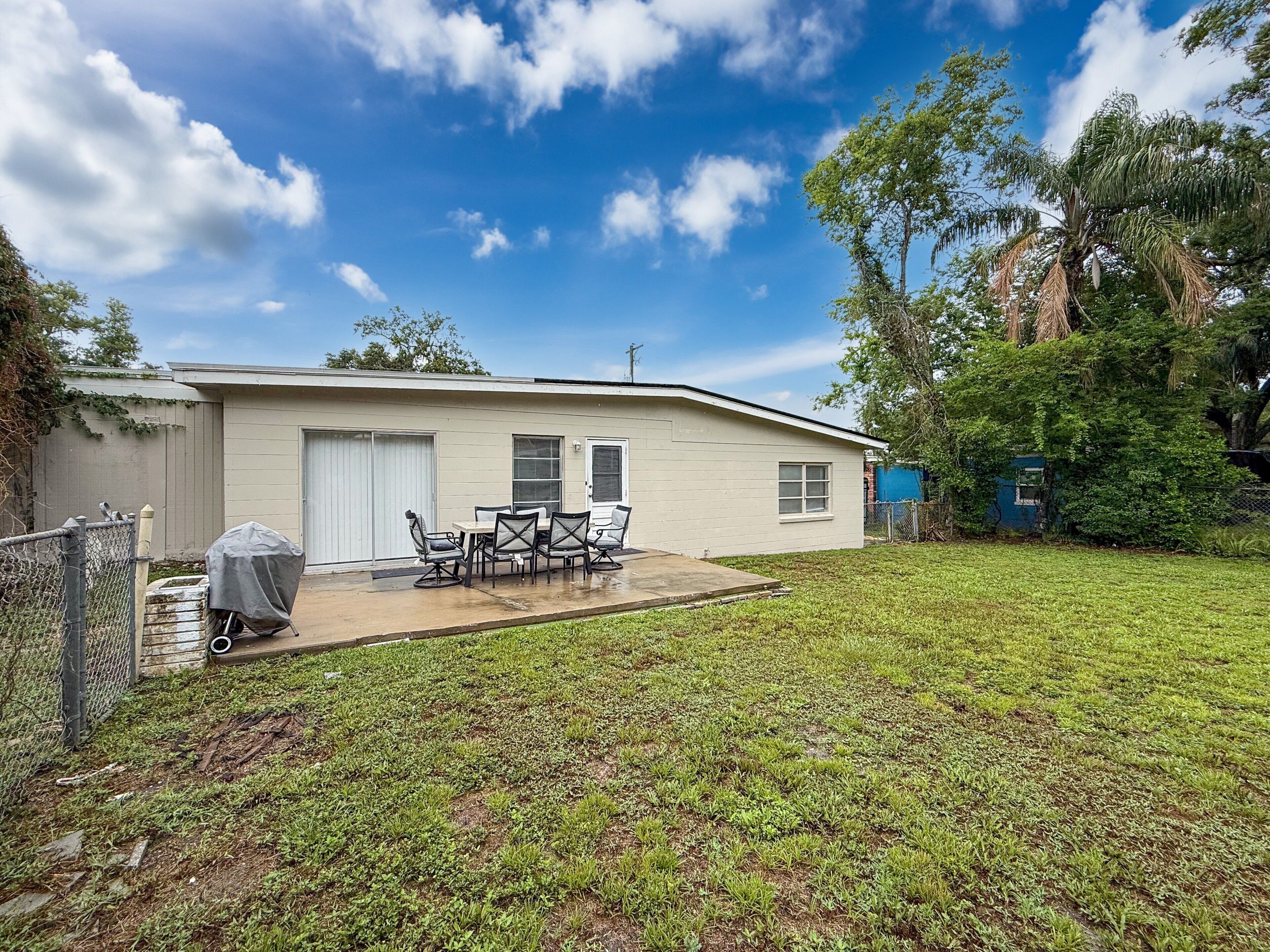 A single-story mobile home with a patio area, a covered grill, and a fenced yard.