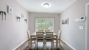 A dining area with a table and chairs, a window with blinds, and wall-mounted electrical outlets. - 3517 River Grove Drive (Tampa)