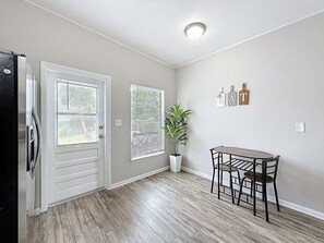 A room with a door, two windows, a potted plant, a table with chairs, and a ceiling light. - 3517 River Grove Drive (Tampa)