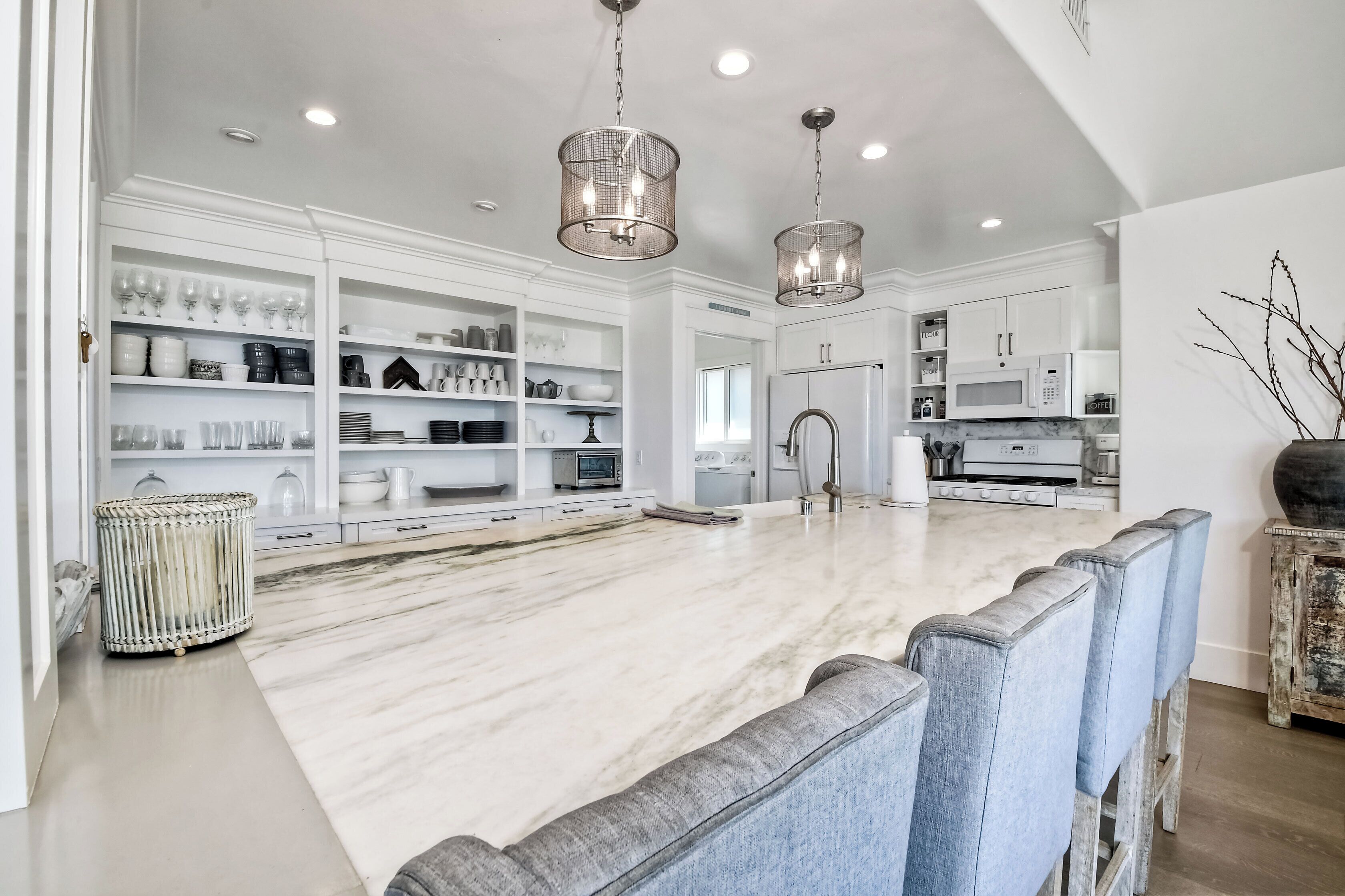 A spacious kitchen with white cabinetry, a marble countertop, and a central island.