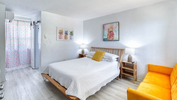 Een slaapkamer met een bed, nachtkastje, stoel en een deur naar een badkamer.