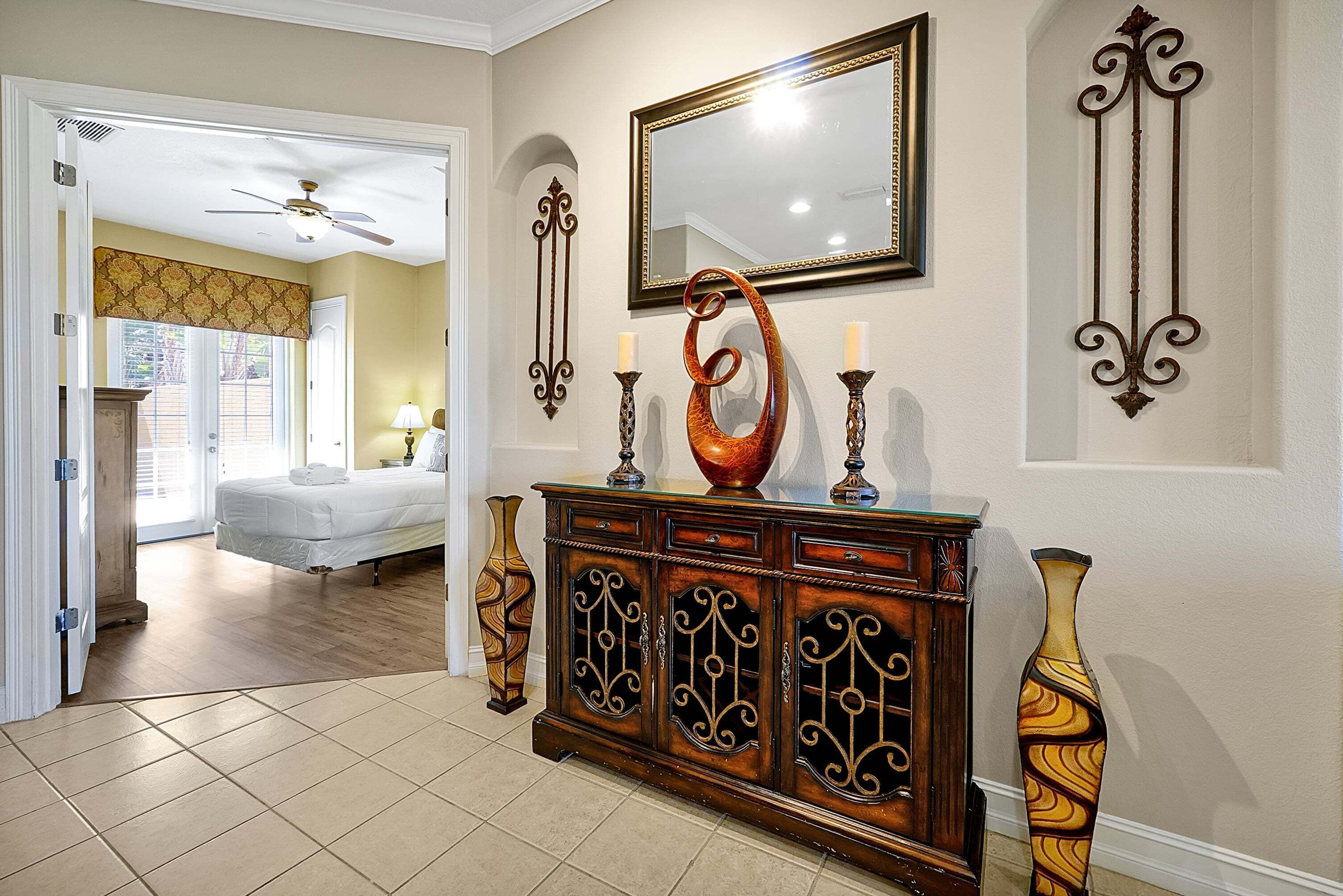 A hotel lobby with a wooden reception desk, a large mirror, and a vase.