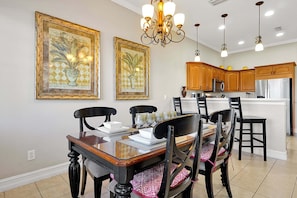 A dining area with a wooden table and chairs, a chandelier, and framed artwork on the wall. - 7407 Excitement DR (Kissimmee)