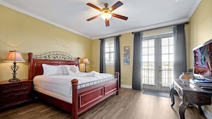 A bedroom with a wooden bed, two bedside tables, a ceiling fan, a nightstand, a desk, and a window with curtains. - 7407 Excitement DR (Kissimmee)