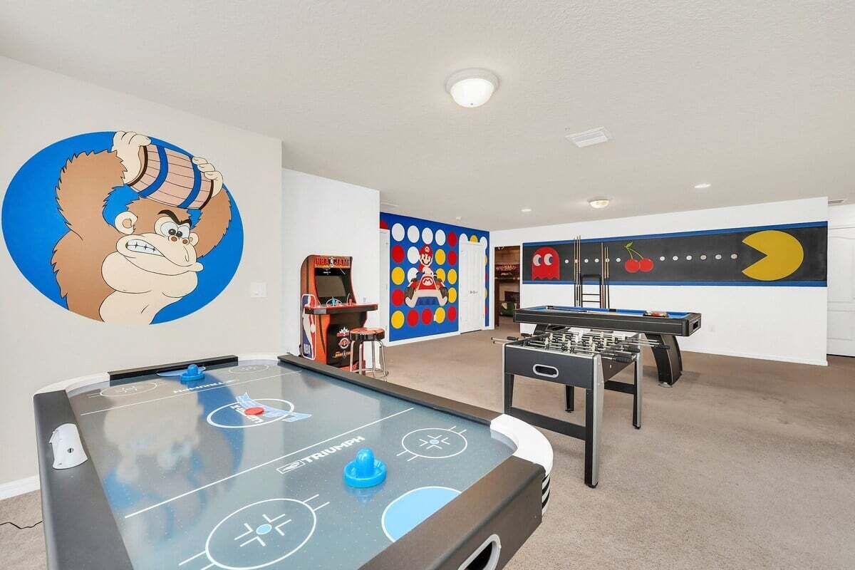 A room with a foosball table, a pool table, and arcade games.