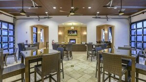 A dining area with tables and chairs, a fireplace, and large windows. - 8872ql-backup · Newly Furnished 9BR Villa With Pool/spa (Kissimmee)