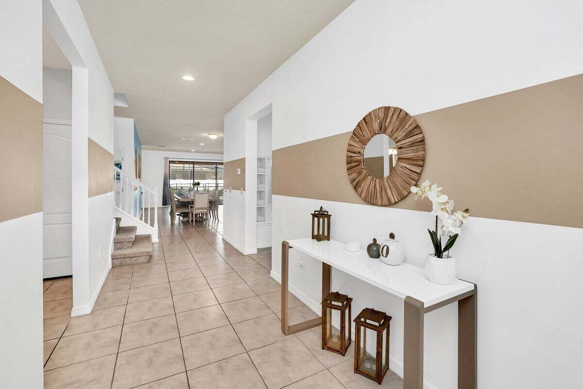 A modern hallway with a white console table, decorative mirror, and potted plants.