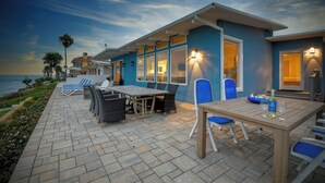 A coastal property with a patio area featuring outdoor furniture and a view of the ocean.