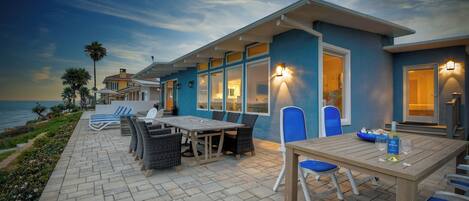 Une propriété située en bord de mer, dotée d’un patio aménagé avec du mobilier d’extérieur et offrant une vue sur l’océan.