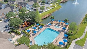 A residential area with a swimming pool, lounge chairs, and a dock over a lake. - 4005 SAN Sabastian Drive 3bed (Kissimmee)