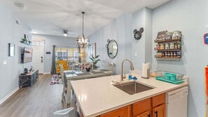 A modern kitchen with a central island, wooden cabinets, a built-in dishwasher, and a dining area with yellow chairs. - 4005 SAN Sabastian Drive 3bed (Kissimmee)