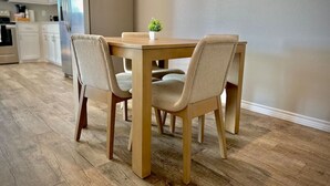 A dining area with a wooden table and four chairs, a small plant on the table, and a kitchen in the background. - A+ for Workers/family,bychoctaw,longstaydiscount (Durant)