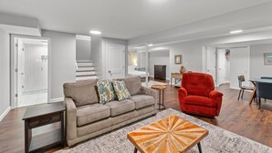 A modern living room with a sofa, armchair, coffee table, and a staircase leading to another level. - 3229 Eads Ave (St. Louis)