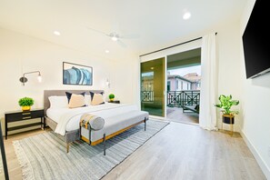 A modern bedroom with a bed, bedside tables, a ceiling fan, and a view of the outside balcony. - 343 Oak Avenue (Carlsbad)