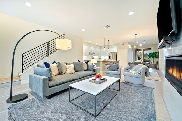 A modern living room with a sofa, armchair, coffee table, and a fireplace. - 343 Oak Avenue (Carlsbad)