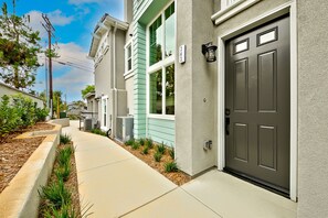 Une rue résidentielle bordée de maisons aux couleurs variées et dotée d’un trottoir bien entretenu.